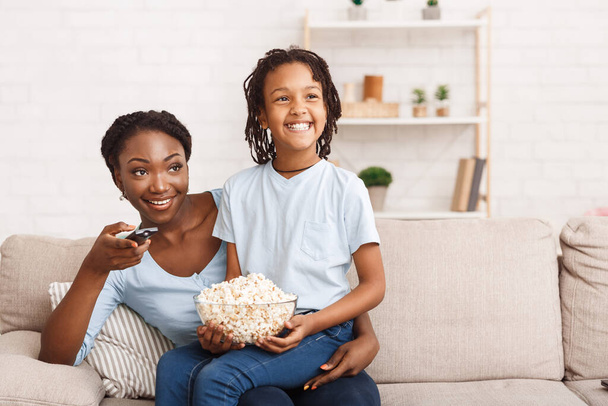 Black family eating popcorn and watching tv together - Photo, image