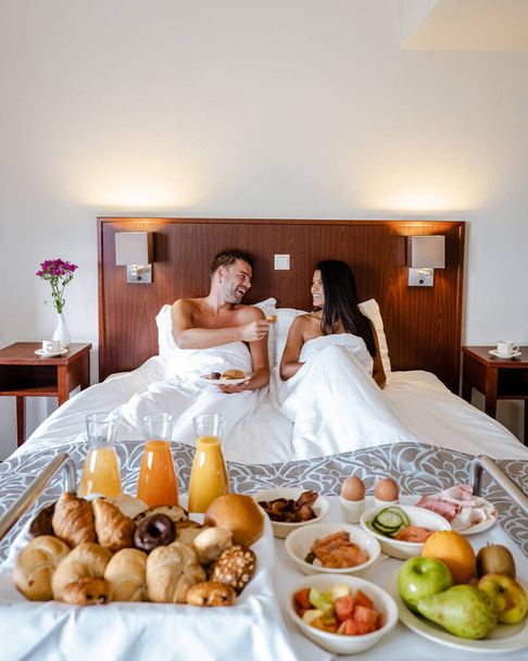 breakfast in bed, couple drinking coffee in bed in the morning at an luxury hotel room - Foto, afbeelding