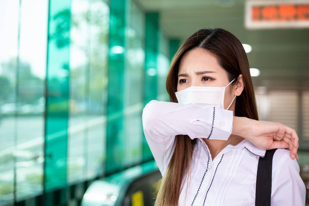 Asian woman cough in elbow with surgical face mask protection - she commutes on the metro or train station - Zdjęcie, obraz