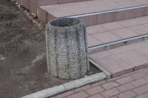 jedna šedá betonová urna stojí na zemi u hnědého chodníku na ulici - Fotografie, Obrázek