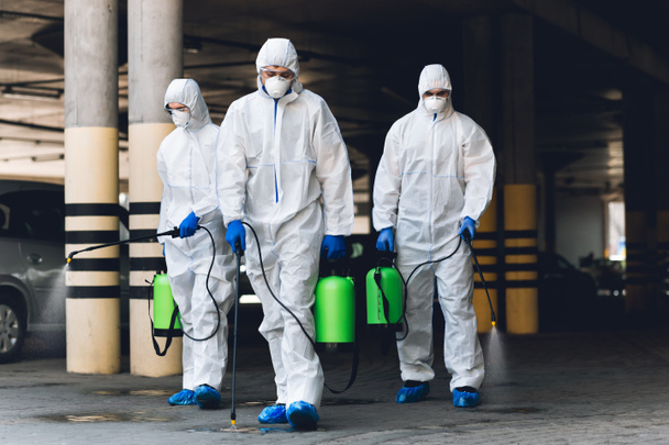 Pracownicy w kombinezonach koronawirusowych oczyszczają ulice chemikaliami - Zdjęcie, obraz