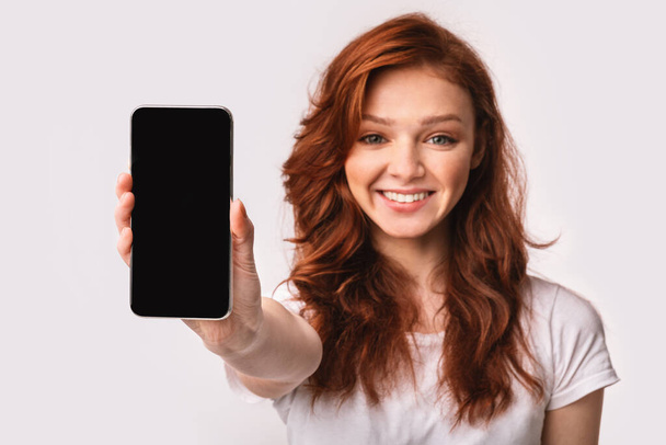 Uśmiechnięta dziewczyna Wyświetlanie Telefonu komórkowego pusty ekran Rekomendowanie aplikacji, Studio Shot - Zdjęcie, obraz