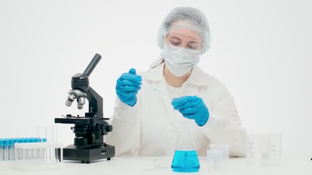 Young female scientist examines a new drug in a glass flask - Πλάνα, βίντεο