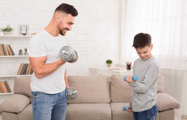 Sportos apa és fia otthon súlyzókkal gyakorol - Fotó, kép