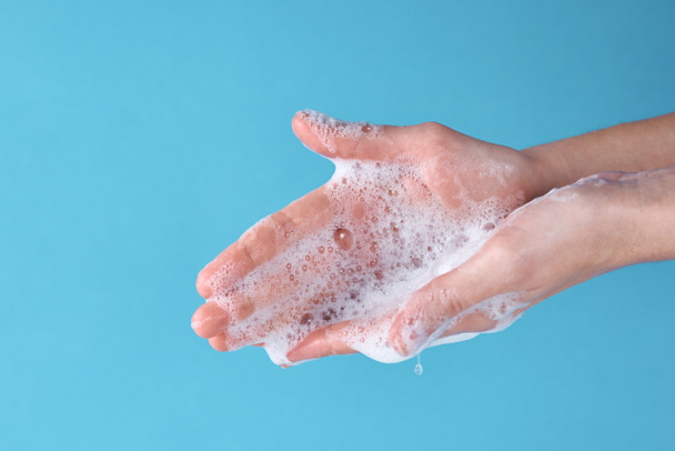 A COVID-19 járványvédelmi koncepciója fertőtlenítőszerrel. Nő kezet mosni szappannal, mint megelőző intézkedés a koronavírus kék alapon - Fotó, kép