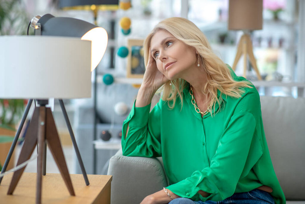Blonde woman in a green blouse looking dreamy - Photo, Image