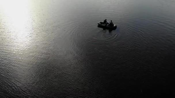 Gün batımında nehirde iki kişiyle birlikte lastik bot yüzüyor. İnsansız hava aracından görüntüle. - Video, Çekim