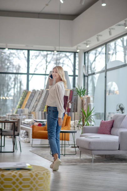 Woman in jeans and white moccasins standing in a furniture salon. - Foto, Imagen