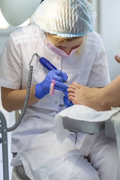 Close-up nagelverzorging door een pedicure specialist in een schoonheidssalon. Pedicure transparante nagelriemen professionele schaar voor pedicure. - Foto, afbeelding