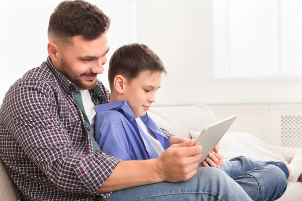 Νεαρός πατέρας παίζει με το γιο του στο ψηφιακό tablet στο σπίτι - Φωτογραφία, εικόνα