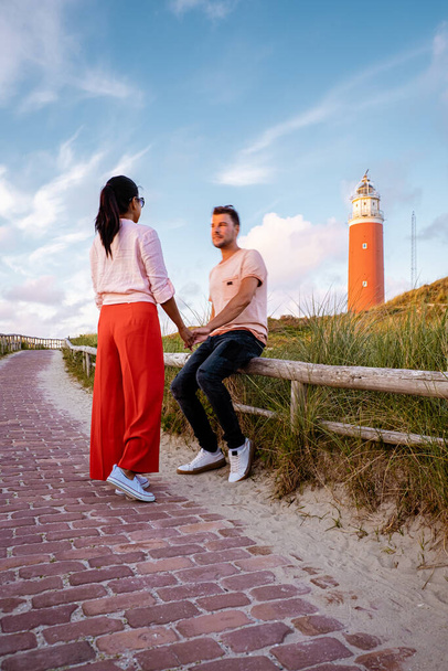 Texel lighthouse during sunset Netherlands Dutch Island Texel, couple visit the lighthouse , men and woman on vacation Texel - Foto, afbeelding