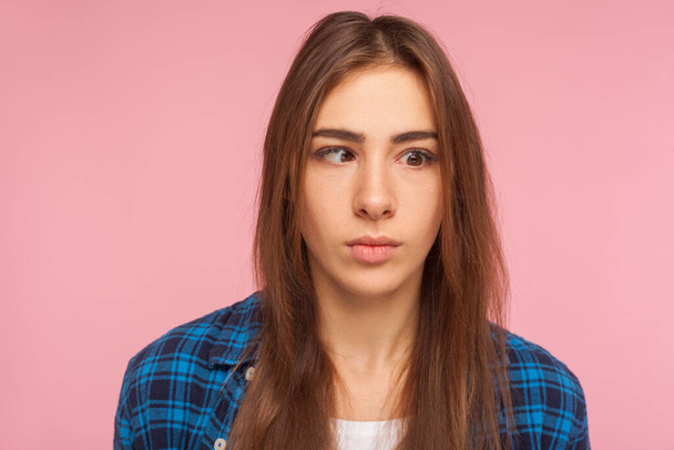 Closeup portrait of positive brunette girl in checkered shirt looking with one crossed eye, making silly awkward face, having fun, childish behavior. indoor studio shot isolated on pink background - Foto, Bild