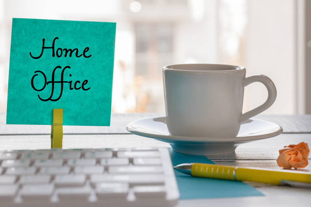 Trabajo remoto en casa durante la epidemia de Coronavirus. Una tarjeta con las palabras "Home Office" y una taza de café, bolígrafo, teclado del ordenador
 - Foto, Imagen
