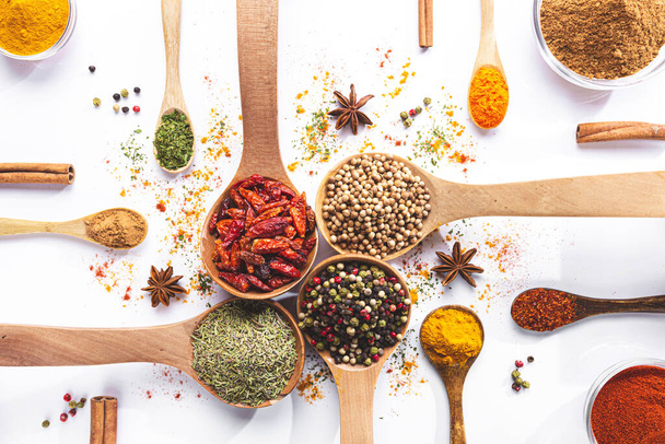 Variety of spices and herbs in spoons and bowls on white background. Top view. Cooking ingredients and condiments concept. - Foto, imagen