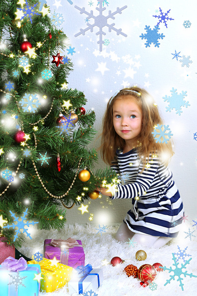 Little girl decorating Christmas tree with baubles in room - Foto, Bild