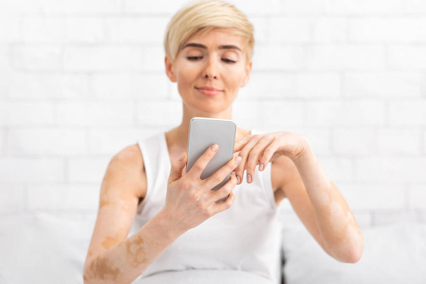 Fröhliche Dame mittleren Alters SMS auf modernem Handy - Foto, Bild