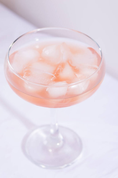 Różowy koktajl z lodem na białym obrusie na stole - Zdjęcie, obraz