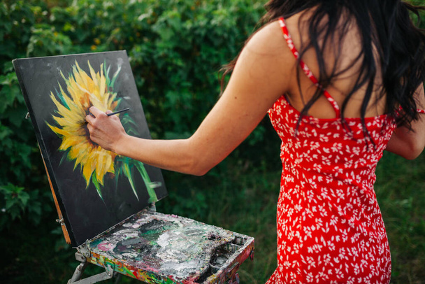 Ser creativo. Mujer artista pintando un girasol en la naturaleza
 - Foto, Imagen