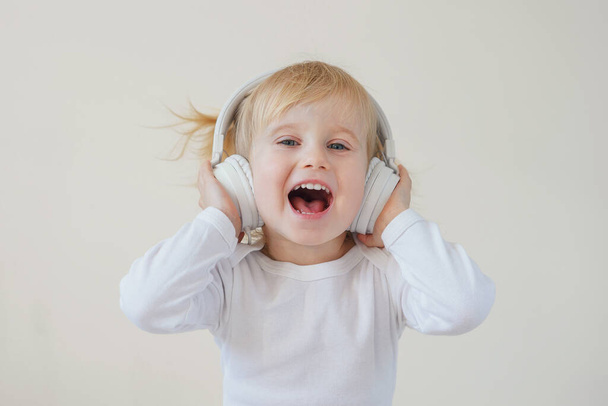 home, technologie en muziek concept - klein meisje met koptelefoon luisteren naar muziek en zingen - Foto, afbeelding