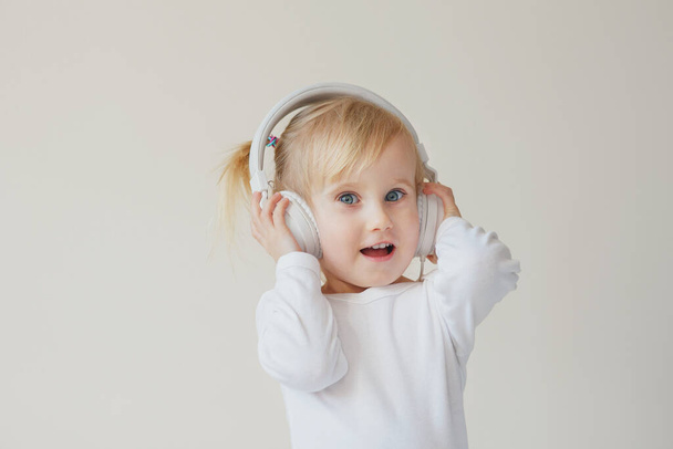 home, technology and music concept - little girl with headphones listening to music and singing - Zdjęcie, obraz