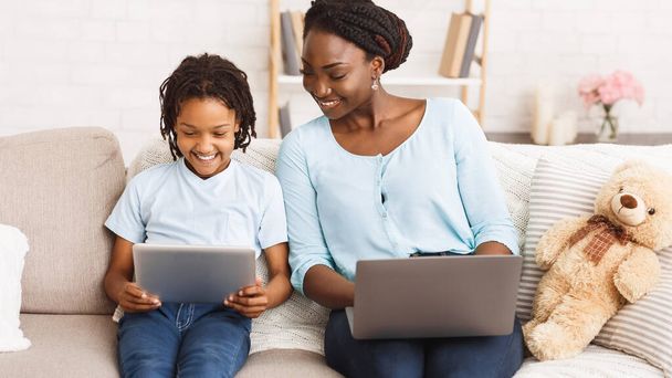 Афро мама и дочь с помощью ноутбука и планшета
 - Фото, изображение
