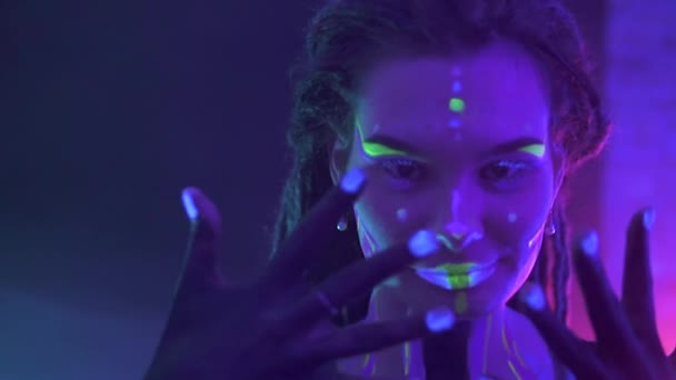 Portrait of a Girl with Dreadlocks in Neon UF Light. Model Girl with Fluorescent Creative Psychedelic MakeUp, Art Design of Female Disco Dancer Model in UV, Colorful Abstract Make-Up. Dancing Lady - 映像、動画