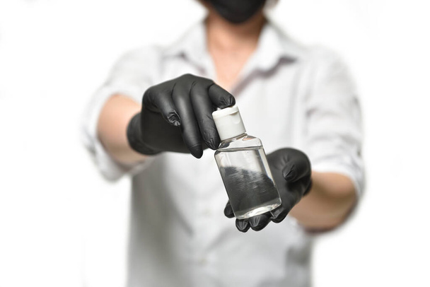A woman in black gloves demonstrates a protective antiseptic gel on a white background, during the coronavirus pandemic. - Zdjęcie, obraz