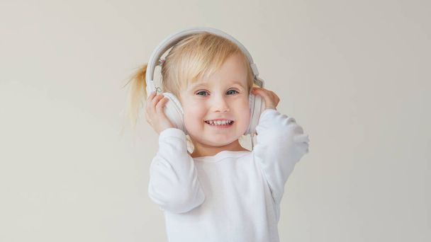home, technology and music concept - little girl with headphones listening to music and singing - Φωτογραφία, εικόνα