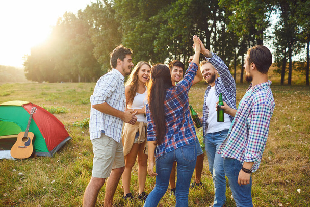 Young people are smiling cheerfully while standing on the grass on picnic - Foto, imagen