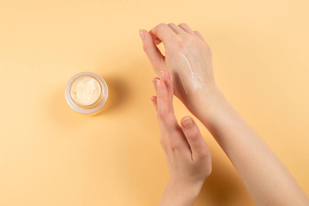Hand cream and woman hands on a beige background. Copy space.  - Photo, Image
