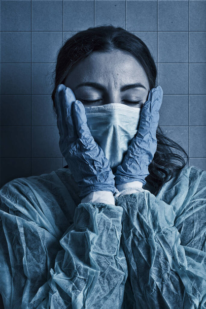 κουρασμένη νοσοκόμα θεραπεία ασθενών με κορωνοϊό, με προστατευτική μάσκα και τα χέρια στο πρόσωπο - Φωτογραφία, εικόνα