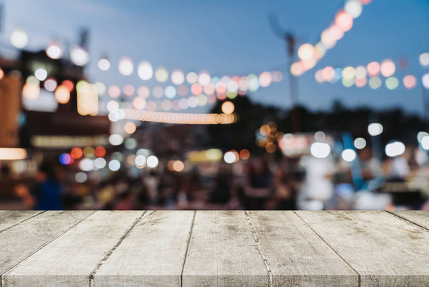 Fából készült asztal és elmosódott háttér éjszaka piacot fesztivál emberek gyalogos úton-val másol hely üres, bemutatás termék montázs. - Fotó, kép