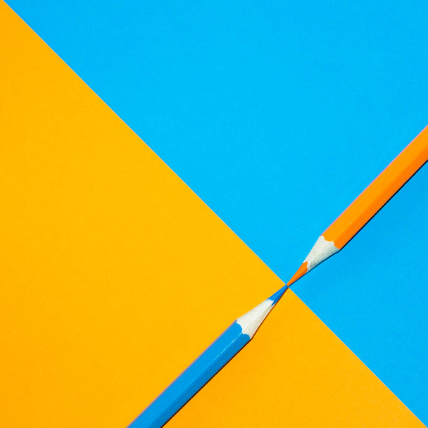 Orange and blue pencil facing each other. Minimal Aesthetic. - Fotó, kép