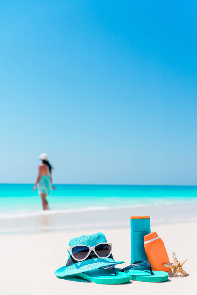 Güneş kremi şişeleri, gözlükler, denizyıldızı ve güneş gözlükleri beyaz kumsal arka planında okyanus. - Fotoğraf, Görsel