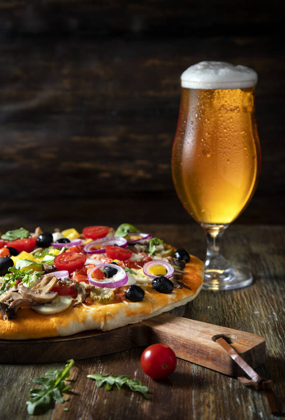 Pizza és egy pohár sör egy fa asztalon. - Fotó, kép