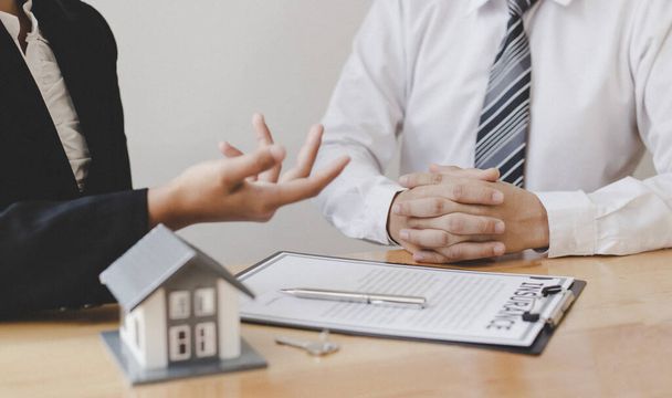 Az ingatlanügynökök azt tanácsolják az ügyfeleknek, hogy hozzanak döntést egy biztosítási ház megvásárlásáról. A beszerzés-értékesítés és a beruházás-tervezés koncepciójának tárgyalása. - Fotó, kép