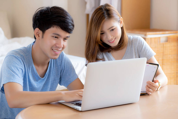 Beautiful young asian couple calculate expenses finance with laptop and planning together, woman writing notebook or note budget household, lifestyle family and business concept. - Photo, Image