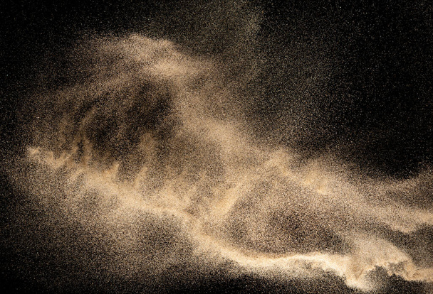 Brun éclaboussures de sable de couleur.Explosion de sable de rivière sèche isolé sur fond noir. Nuage de sable abstrait
. - Photo, image