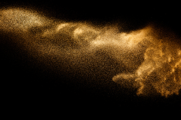 Arany homokrobbanás elszigetelt fekete háttérrel. Absztrakt homokfelhő. Homokos légy hullám a levegőben. - Fotó, kép