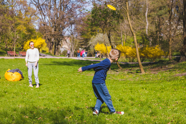 Äiti aurinko pelaa frisbee keväällä aurinkoinen puisto kopioi tilaa
 - Valokuva, kuva
