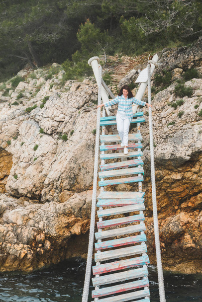 jeune jolie femme adulte en vêtements blancs avec chemise bleue au pont suspendu en plein air Voyage point de repère à pula croatia - Photo, image