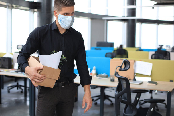 Dismissal employee in an epidemic coronavirus covid-19. Dismissed worker going from the office with his office supplies - Φωτογραφία, εικόνα