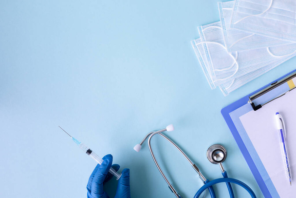 Mavi arka planda tıbbi konsept. Stetoskop, hap, tablet, not defteri, kağıt, kalem. Tıbbi eldivenler. Tıbbi maske. Boşluğu kopyala - Fotoğraf, Görsel