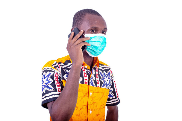 jeune homme portant un masque médical sur le visage et parlant sur un téléphone portable
. - Photo, image