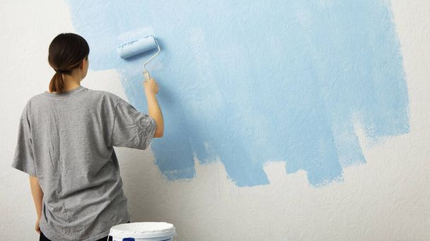 Woman paint wall at home, free space - Valokuva, kuva