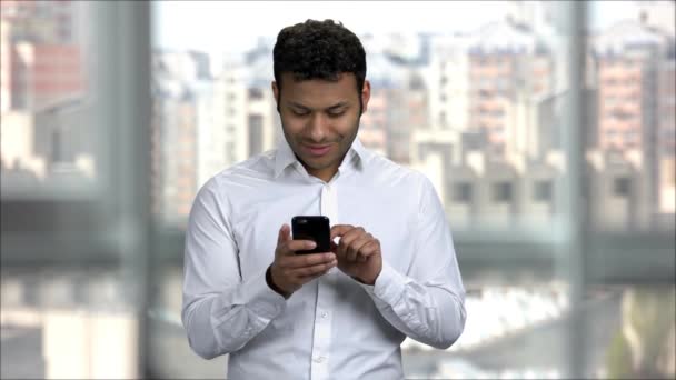 Indiai fiatal srác szórakoztató a szociális média az irodában segítségével smartphone. - Felvétel, videó