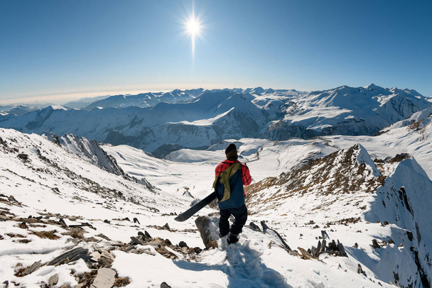 snowboarder olha para baixo em picos cobertos de neve de montanhas
. - Foto, Imagem