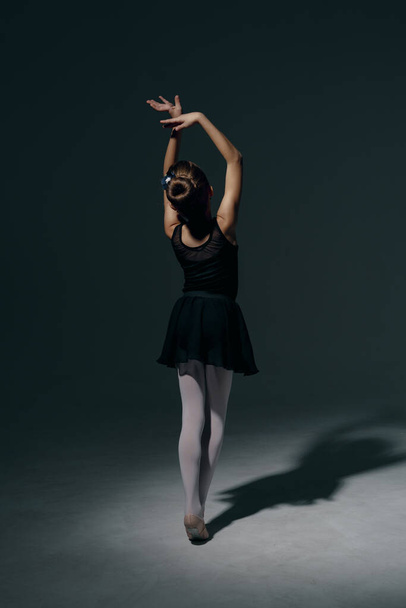 Όμορφη κοπέλα μπαλαρίνα χορό στο παιχνίδι φως και σκιά σκούρο φόντο - Φωτογραφία, εικόνα