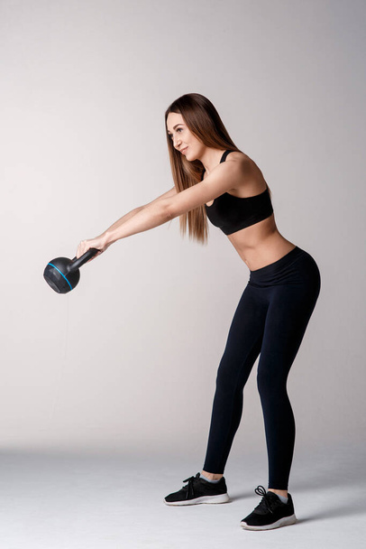 Athletic woman with kettlebell doing a lunges. Photo of latin woman in silhouette isolated on white background. Strength and motivation. Side view. - Valokuva, kuva