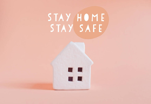 white house with motivation quote stay home stay safe to prevent the spread of covid-19 and coronavirus on peach color background   - 写真・画像
